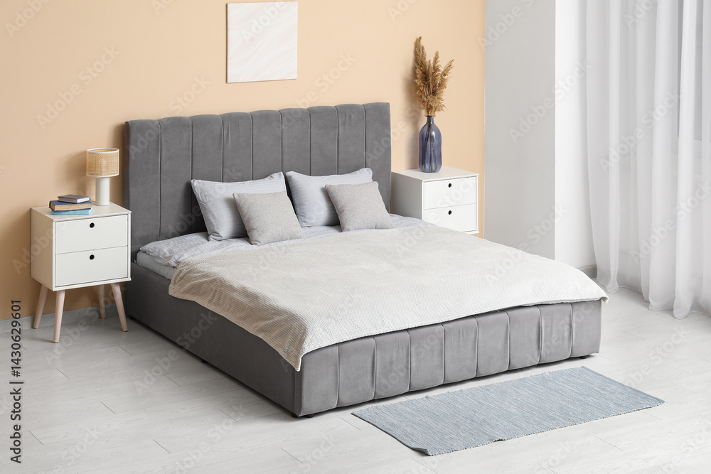 Beautiful bedroom with comfortable bed, bedside tables and vase of pampas grass