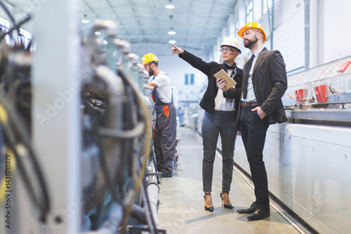 Quality inspectors team and workers at factory using machines