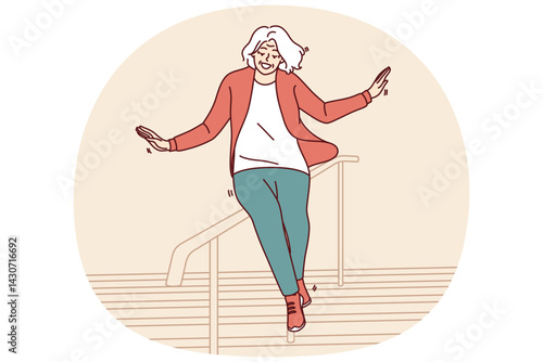 Elderly woman slides down stair railing having fun and being active after retirement. Cheerful elderly woman in casual clothes feels full of energy and laughs regardless of mature age