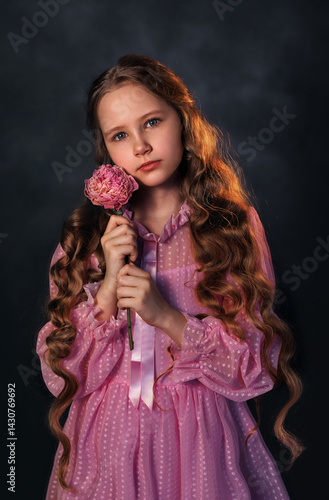 Obraz na płótnie Beautiful girl in a pink dress with a peony flower on a dark background. Romantic, festive image w salonie