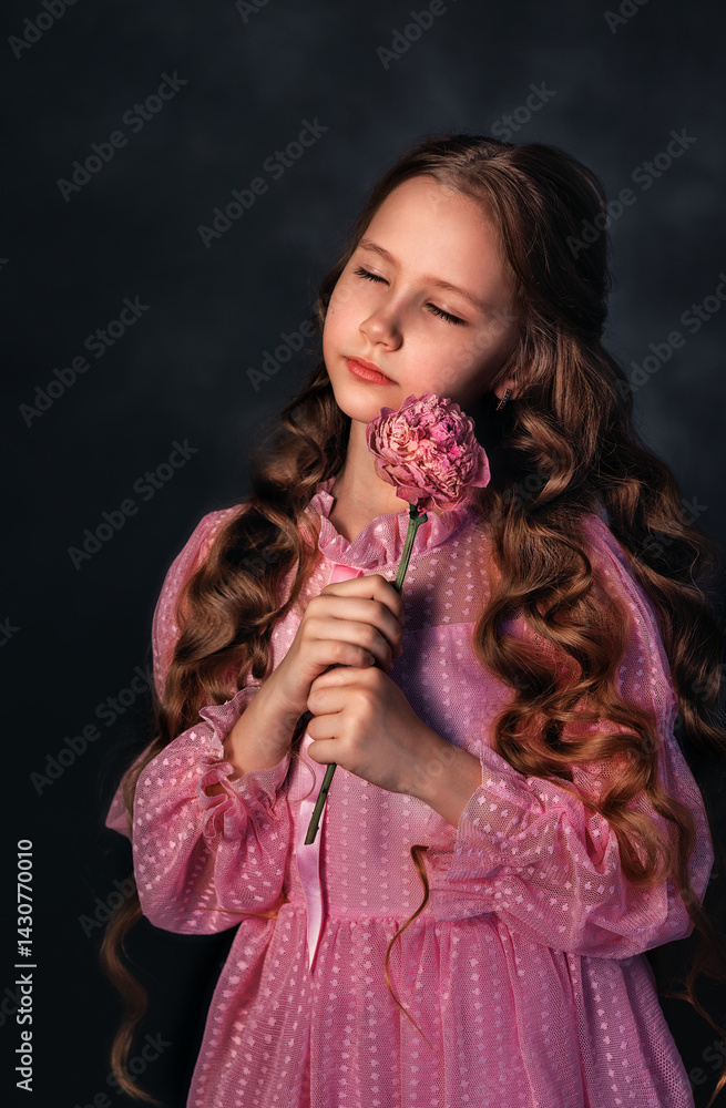Beautiful girl in a pink dress with a peony flower on a dark background. Romantic, festive image