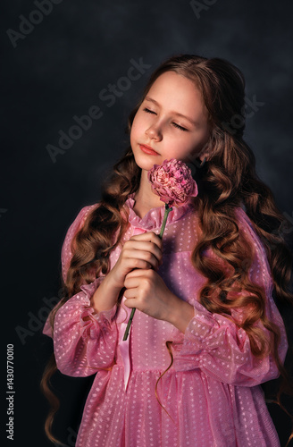 Obraz na płótnie Beautiful girl in a pink dress with a peony flower on a dark background. Romantic, festive image w salonie