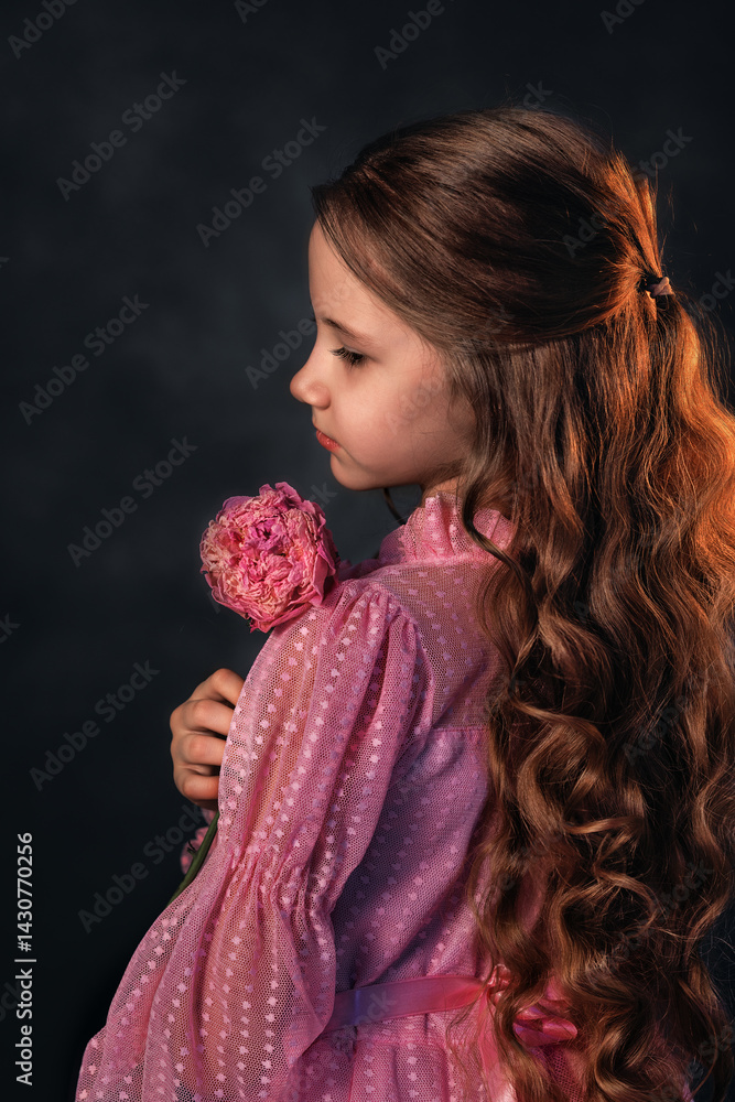 Beautiful girl in a pink dress with a peony flower on a dark background. Romantic, festive image