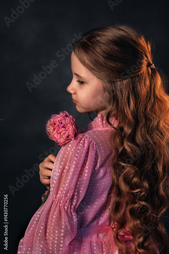 Obraz na płótnie Beautiful girl in a pink dress with a peony flower on a dark background. Romantic, festive image w salonie