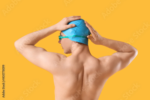 Male swimmer on yellow background, back view