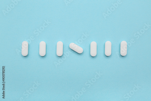 Many white pills on blue ba...