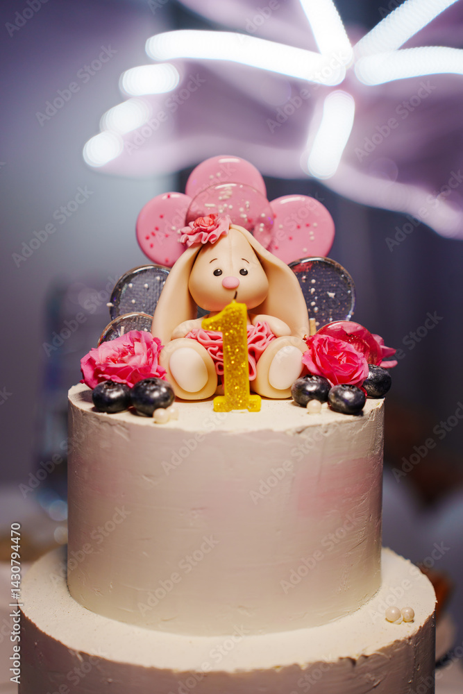 Children's festive two-tiered cake decorated with flowers and a bunny for a girl