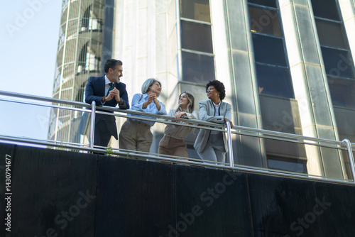Business people talking on balcony of modern office building
