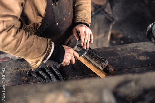 Tableau sur toile Caucasian blacksmith sharpens knife blade on whetstone, sharpening stone at trad