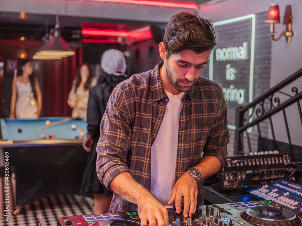 Stylish young DJ performing live in an urban nightlife setting. Dressed in casual fashion, he mixes tracks with professional gear at a trendy bar.