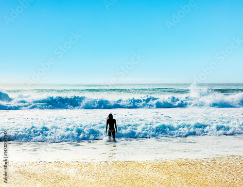 silhouette einer surferin am Strand vor einer Welle