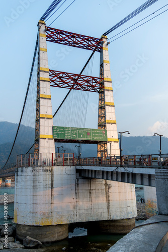 The beginning of Janki Setu bridge in Rishikesh features the first pillar, marking the start of this significant structure. The area is lively.