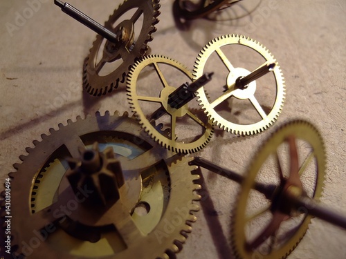 Close-up of vintage brass clock gears and mechanisms arranged on a textured surface, showcasing intricate engineering and craftsmanship