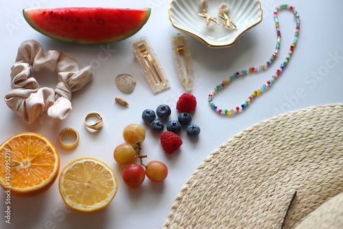 Straw hat, sunglasses, seasonal fruit, seashells and colorful accessories on white backgrounds. Cute summer essentials. Selective focus.