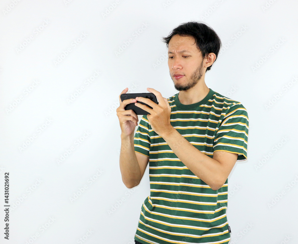 Man Concentrating While Playing Game on Phone Against White Background Man Concentrating While Playing Game on Phone Against White Background