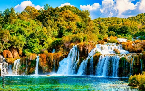 The enchanting Krka waterfalls cascade through lush green landscapes, creating a serene atmosphere during a warm summer evening at sunset in Krka National Park, Croatia.