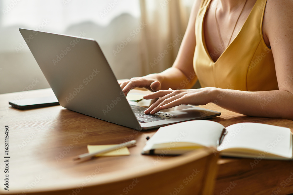 Fototapeta premium Young beautiful woman working on a laptop at a cozy wooden table during daylight hours
