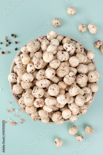 Bowl of makhana, fox nut or lotus seeds rich in protein with salt and pepper on blue background. Top view. Close up. Indian food.