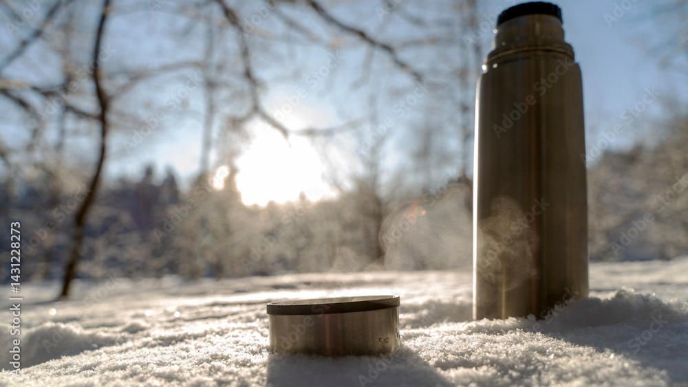 Fototapeta premium Thermo with hot tea in the snow in the winter forest