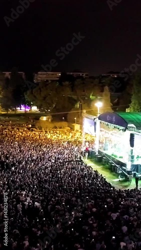 Vertical video at the concert - High quality aerial view of people having fun at the concert, concert stage and stage lights, lasers taken by drone