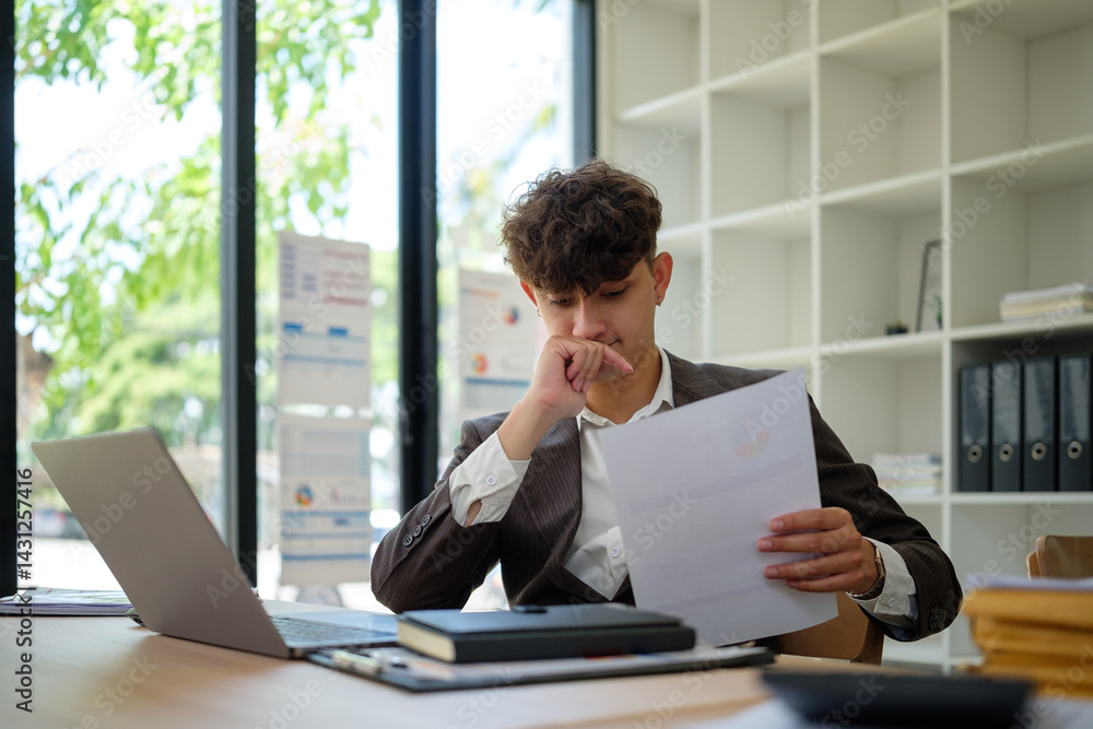 Fototapeta premium Thoughtful businessmman reading financial report at office desk.