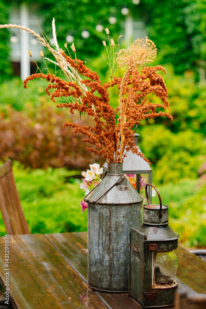 Bouquet of dried flowers in a vintage balloon on a wooden table in the garden.