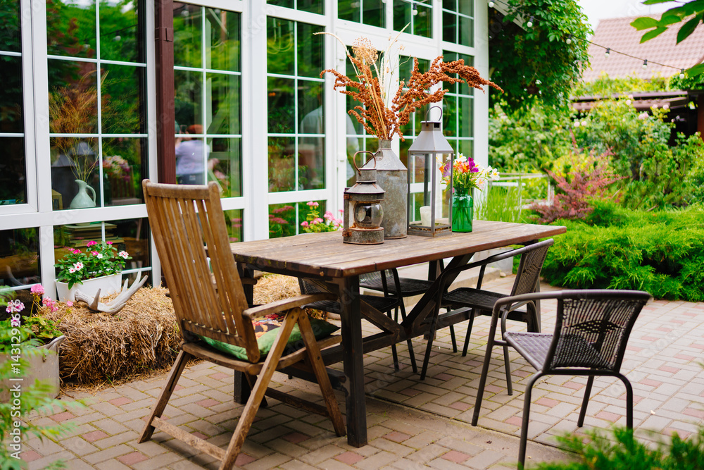 wooden table with lanterns and dried flowers. The yard in the house.