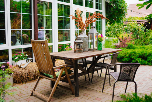 wooden table with lanterns and dried flowers. The yard in the house.