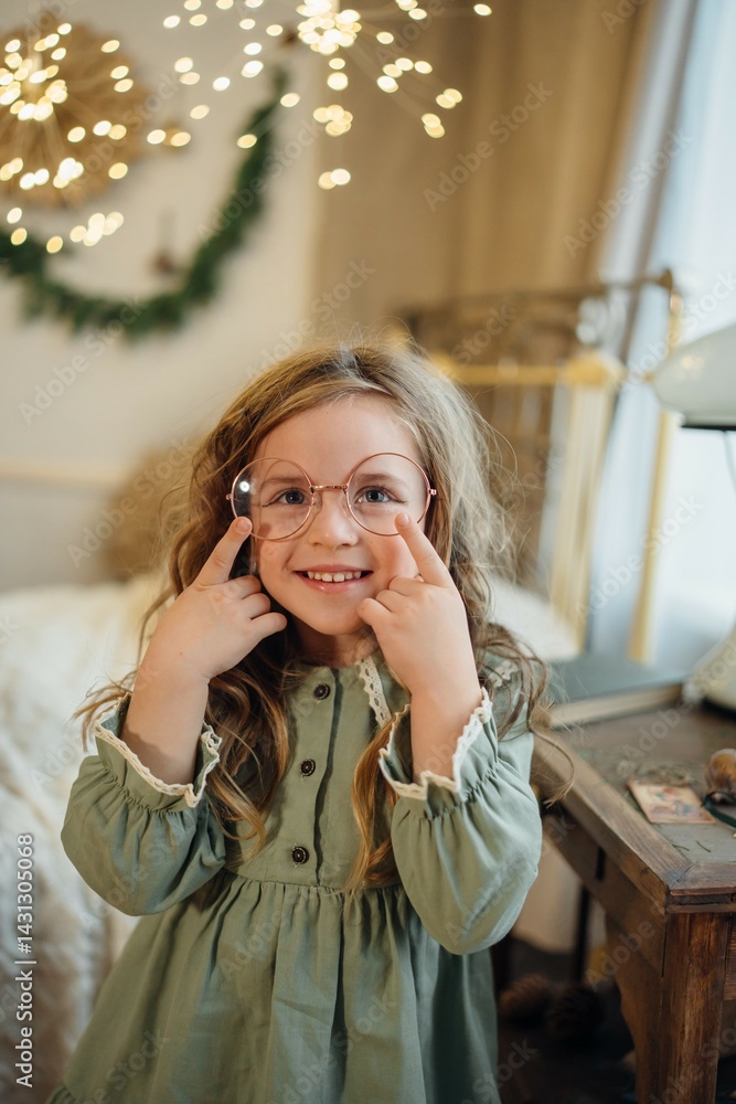A beautiful little girl in a green dress and large round glasses.