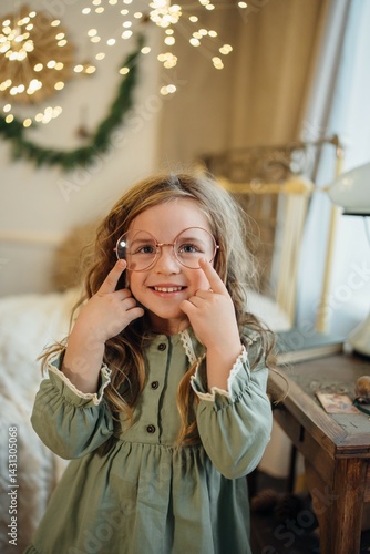 Obraz na płótnie A beautiful little girl in a green dress and large round glasses. w salonie