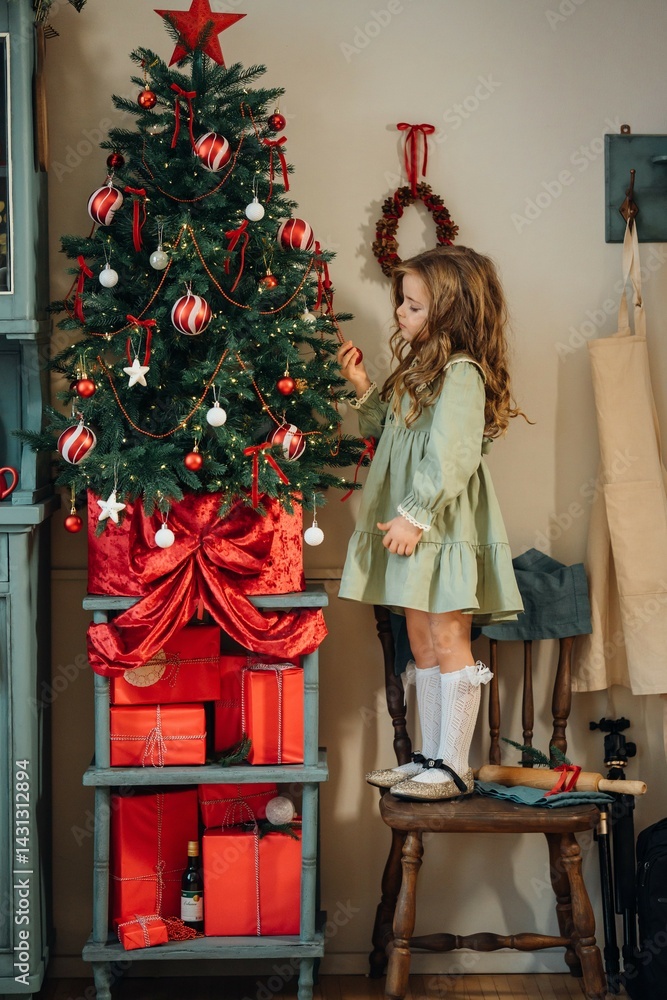 Beautiful little girl decorates a christmas tree