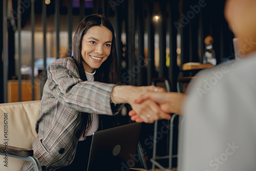 Quadro em tela A professional woman in a stylish blazer confidently shaking hands within a cont