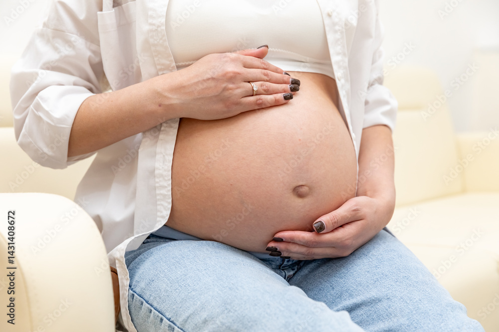 Close up pregnant woman gently touching her belly, sitting on sofa in a cozy home, showing maternal love and anticipation. Captures love, care, and connection during pregnancy. Footage with copy space