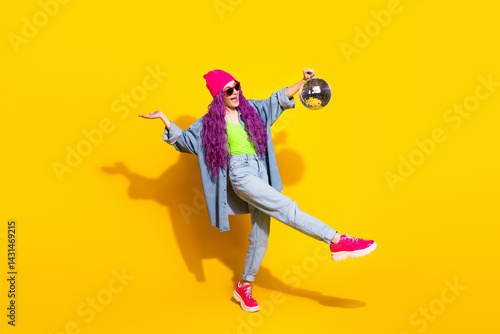 Wallpaper Mural Trendy woman with bright pink hair and stylish outfit posing playfully against a vibrant yellow background, holding a shiny disco ball Torontodigital.ca