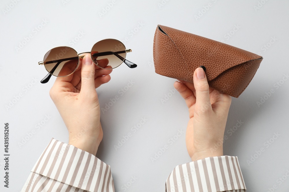 Woman with sunglasses and case on light grey background, top view