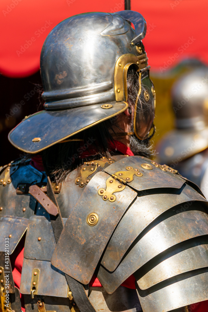 Fototapeta premium close view of a roman military helmet and shoulder armor, segmented roman armor and red tunic