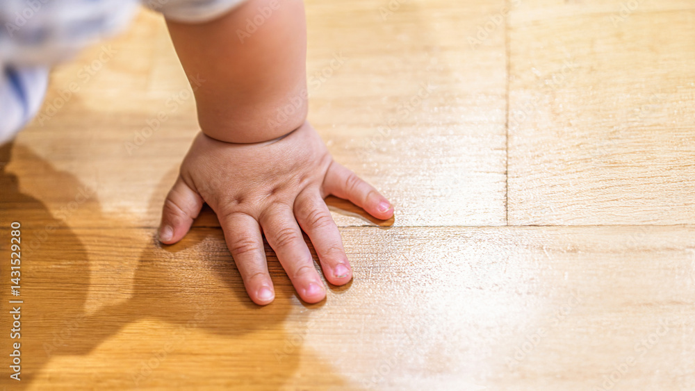 Small baby hand pressing on polished wooden floor close-up, concept of childhood and innocence Small baby hand pressing on polished wooden floor close-up, concept of childhood and innocence