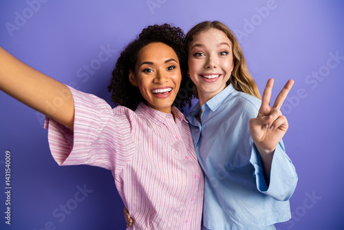 Konstfotografi Young female friends taking a cheerful selfie against a purple background while celebrating together in stylish and casual outfits