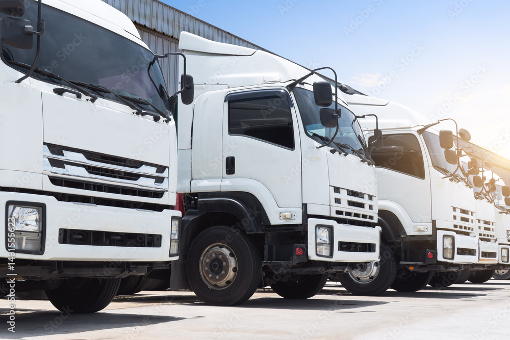 Obraz premium Trucks Parked Parked on The Parking Lot at Warehouse. Big Rig, Shipping Trucks, Distribution Warehouse. Economy Business Transport on Road. Trucking. Freight Logistics Truck Transportation.