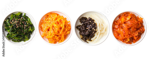Colorful Korean side dishes in small bowls. Top view of four traditional Korean banchan dishes including seaweed, pickled radish, and spicy fermented vegetables in white bowls.