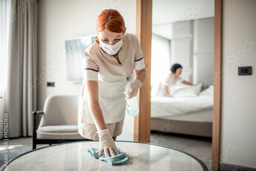 Hotel housekeeping staff cleaning room with protective mask and gloves