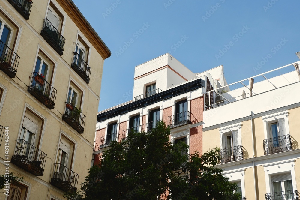 Colorful buildings with wrought iron balconies rise against a bright blue sky in a picturesque street in Madrid, Spain Colorful buildings with wrought iron balconies rise against a bright blue sky in a picturesque street in Madrid, Spain