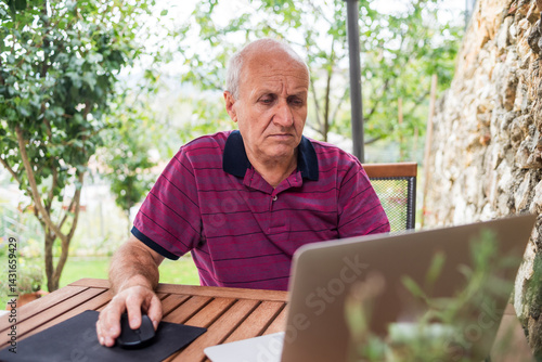 Old Man using laptop on garden work from home