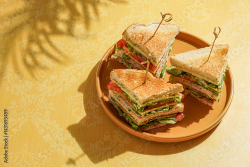club sandwich served on a wooden cutting board. The sandwich is layered with crispy toasted bread, fresh lettuce, ripe tomatoes, slices of ham, and cheese