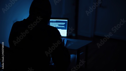 Hacker hacks programs. Computer scammer. Programmers working intently on laptop, typing in dark room with shadowy atmosphere, evoking cybersecurity intensity and digital intrigue