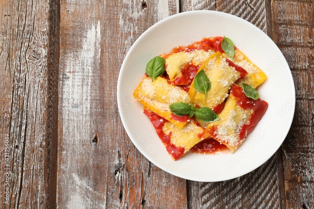 Delicious ravioli with tomato sauce, parmesan cheese and basil on wooden table, top view. Space for text Delicious ravioli with tomato sauce, parmesan cheese and basil on wooden table, top view. Space for text