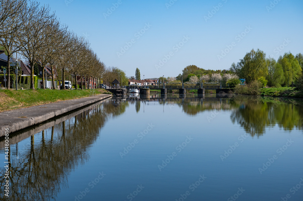 Boats and houses reflecting in the water of the river Lys or Leie in Menen, West Flanders, Belgium Boats and houses reflecting in the water of the river Lys or Leie in Menen, West Flanders, Belgium