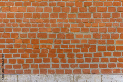 A red brick wall with a white base. The bricks are laid in a pattern.