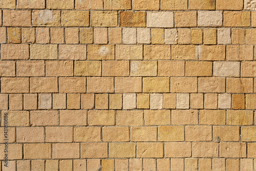 The brick wall is brown and yellow. The bricks are laid unevenly.