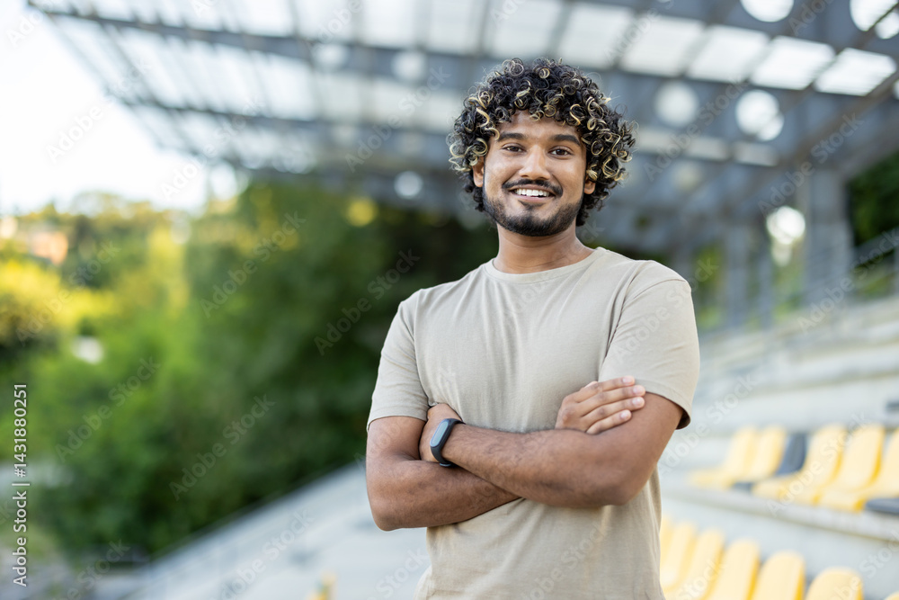 Portrait of a young athlete, a man in sportswear smiling and looking at the camera with crossed arms, during fitness and active physical exercises.